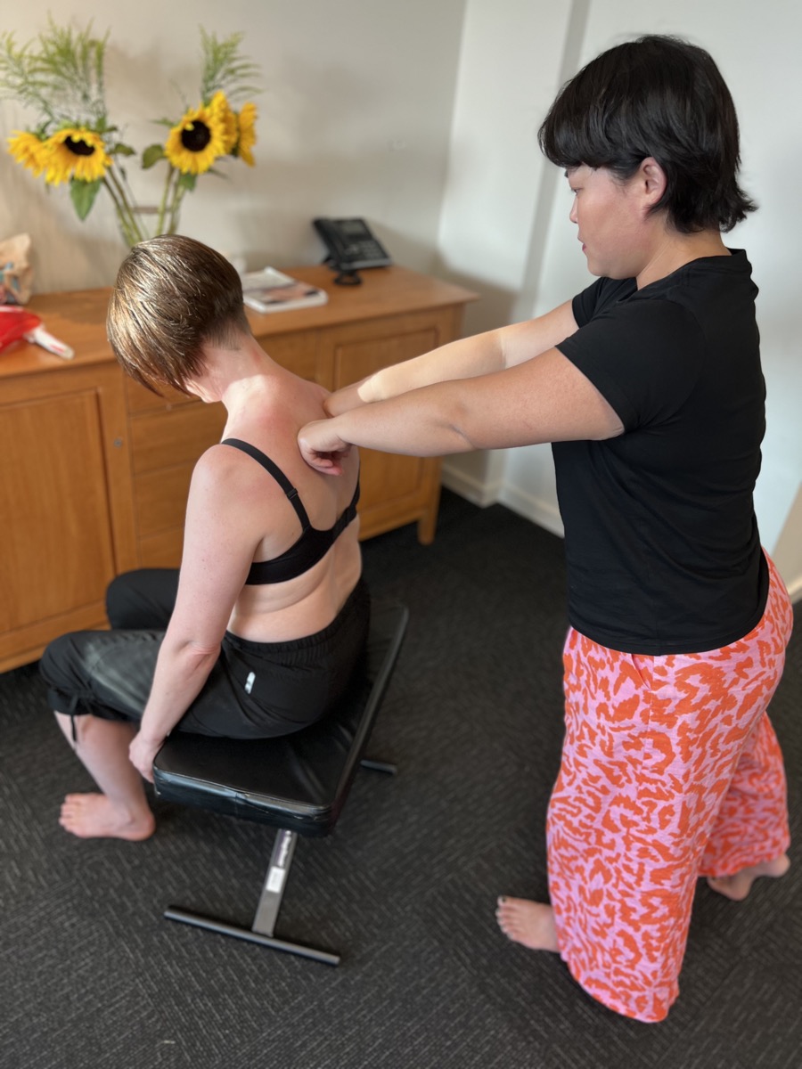 Kiki Ruan working on a client's shoulder during a structural integration session